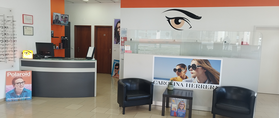 Interior da Ideal Óptica da Malveira — balcão de atendimento, expositores de óculos e área de espera